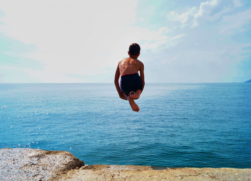 Ένα αγόρι κάνει βουτιά στη θάλασσα στις καλοκαιρινές διακοπές